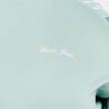 Close-up of a light teal garment featuring a small white Ron Jon logo near the shoulder.