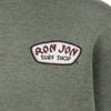 Close-up of a gray-green fabric featuring a Ron Jon Surf Shop patch with red and black text outlined in white.