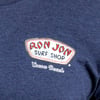 Close-up of a blue shirt featuring a Ron Jon Surf Shop logo with Cocoa Beach written below.