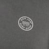 Close-up of a gray fabric with a white circular logo reading Ron Jon Surf Shop Est. 1959 and wavy lines inside.