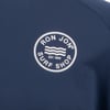 Close-up of a navy blue fabric with a Ron Jon Surf Shop logo. The logo is a white circle with text RON JON SURF SHOP EST. 1959 and wavy lines inside.