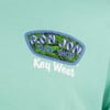 Close-up of a green T-shirt with a blue and green Ron Jon Surf Shop logo, featuring Key West written in white below.