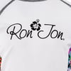 White fabric featuring the Ron Jon logo in black script with a hibiscus flower between the words.