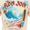 T-shirt design featuring a surf wave, floral border, and a surfboard. Text: Ron Jon Surf Shop, Cocoa Beach, FL.