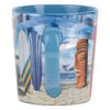 A blue ceramic mug with a beach-themed design featuring surfboards, waves, a tiki statue, and sand. The mugs handle is centered in the image.
