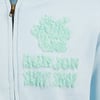 Light blue jacket with a zipper, featuring a textured mint green emblem and text on the front.