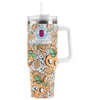 Tall insulated tumbler with white handle and straw, featuring a colorful pattern of orange slices, flowers, and cartoon faces on an orange background.