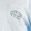 Close-up of a light blue shirt pocket with a Ron Jon Surf Shop logo printed on the pocket.