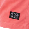 Close-up of a pink fabric with a black label that reads RON JON SURF SHOP, featuring a small palm tree graphic.