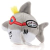 Ron Jon Surf Shop plush toy resembling a shark, featuring red goggles, a yellow tuft of hair, dorsal fin, and branded side patch.
