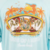 A blue shirt featuring a colorful Ron Jon Surf Shop logo with palm trees, a female surfer, flowers, and the text One of a Kind Cocoa Beach.