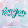 Close-up of a Ron Jon Surf Shop cap with teal embroidered logo on a colorful, patterned background.