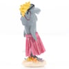 A figurine of a gray shark wearing a pink grass skirt, yellow wig, and sunglasses, standing upright on a sandy base with seashells and starfish.