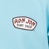 Close-up of a light blue T-shirt featuring the Ron Jon Surf Shop logo in red letters over a white background.