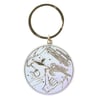 A round metallic keychain with engraved images of a shark, a sea turtle, a van, a hand in a shaka sign, and ocean-themed elements.