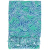 A folded turquoise fabric with a blue and white abstract leaf pattern and fringed tassels at the edge.