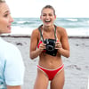 girls having fun at the beach, one taking pictures of the other