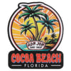 A colorful sign featuring palm trees, a sunset, and Ron Jon Surf Shop above the text Cocoa Beach Florida.