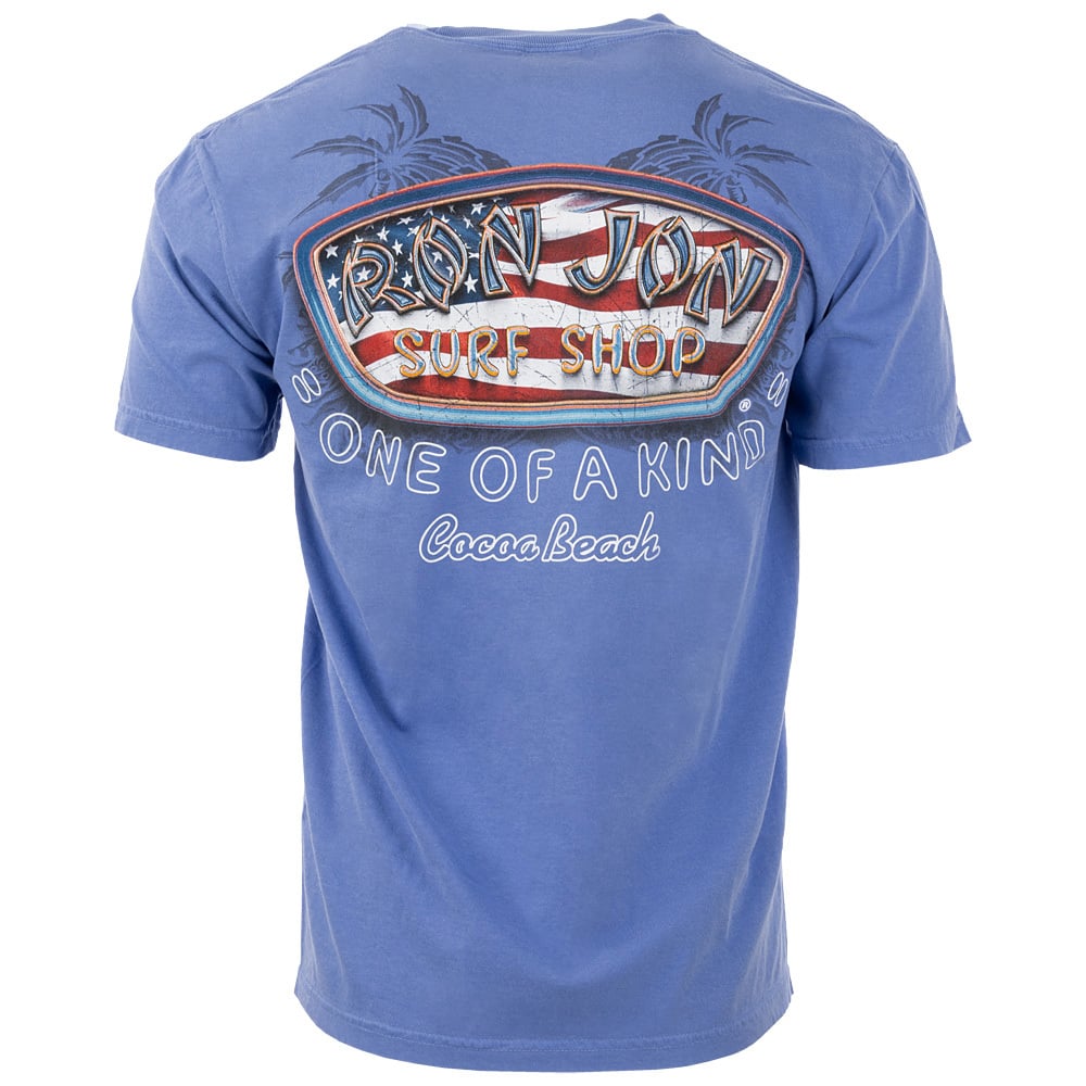 Back view of a blue Ron Jon Surf Shop T-shirt featuring an American flag design, palm tree outlines, and the text One of a Kind, Cocoa Beach.
