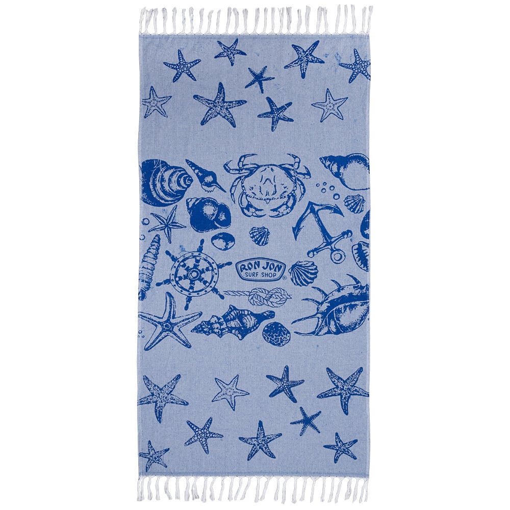 A blue beach towel with white fringe, featuring dark blue illustrations of seashells, starfish, crabs, an anchor, and Ron Jon Surf Shop text in the center.