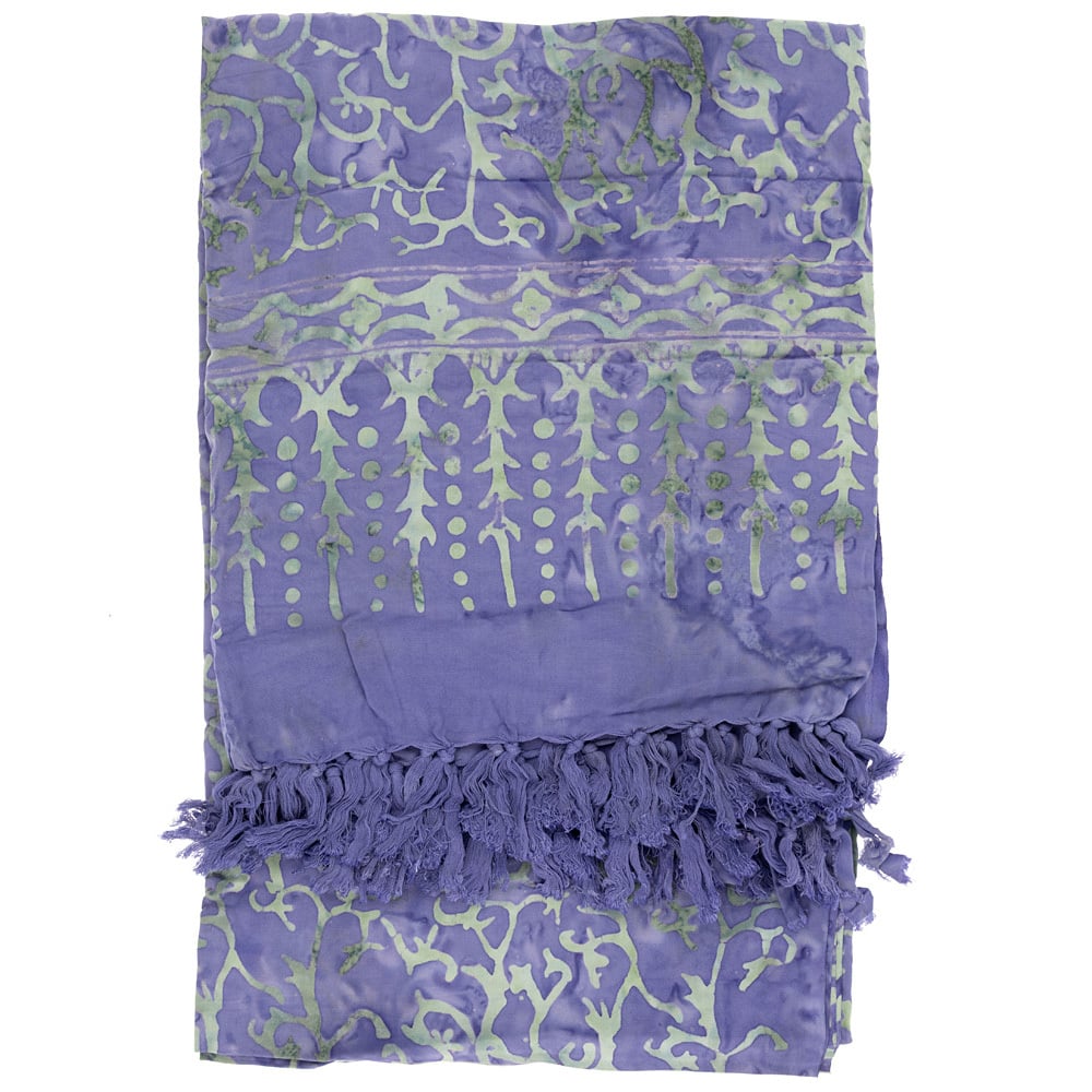 A folded lavender fabric with light green leaf and vine patterns, featuring a tasseled fringe on one end.