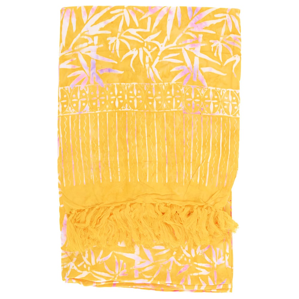 A yellow and white patterned fabric with a leafy design, vertical lines, and fringed ends, folded neatly.