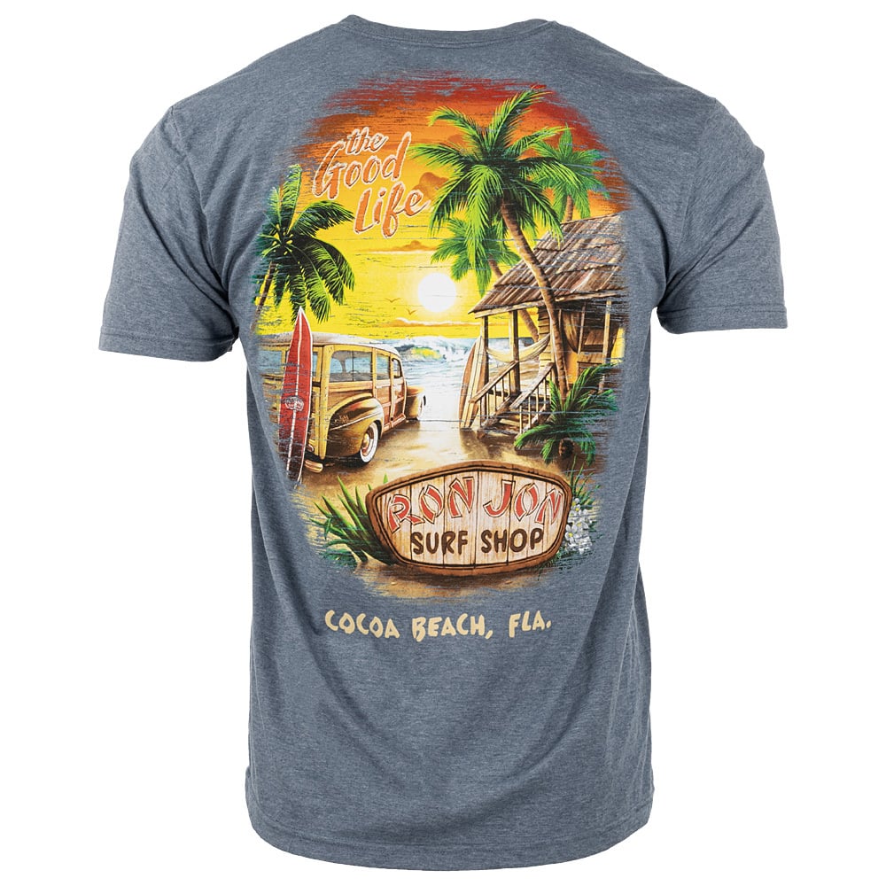 Gray blue t-shirt featuring a colorful beach scene with a surfboard, wooden car, palm trees, and a hut. Text reads: “The Good Life,” “Ron Jon Surf Shop,” and “Cocoa Beach, Fla.”.