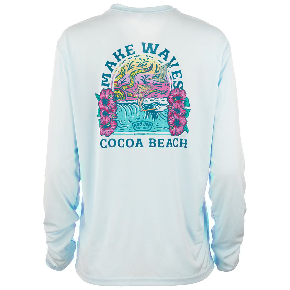 A light blue long-sleeve shirt with a colorful Make Waves Cocoa Beach graphic, featuring ocean waves, flowers, and a sunset on the back.