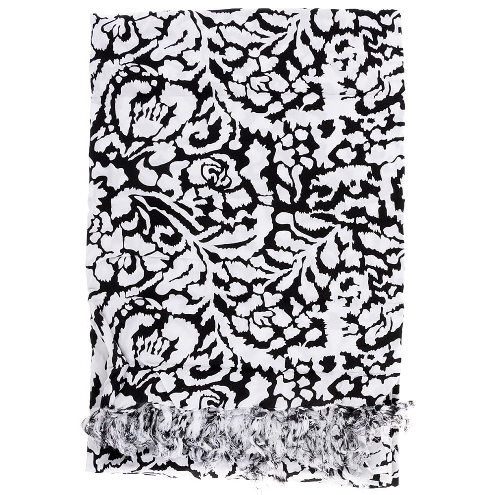 A black and white patterned fabric with abstract designs and fringed edges is neatly folded.