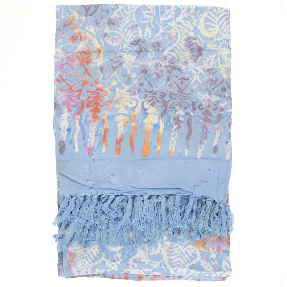 Light blue sarong with a colorful, abstract floral pattern and fringed tassels on one end, laid flat against a white background.