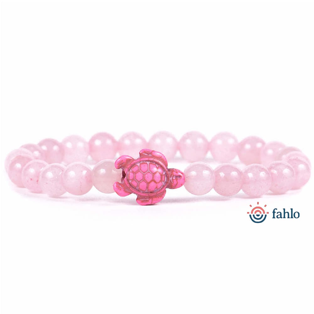 A beaded bracelet with pink round beads and a pink turtle charm in the center, shown on a white background with the Fahlo logo.