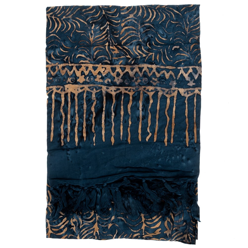 A folded dark blue scarf with abstract tan patterns and fringe on one end. The designs include wavy and geometric motifs.
