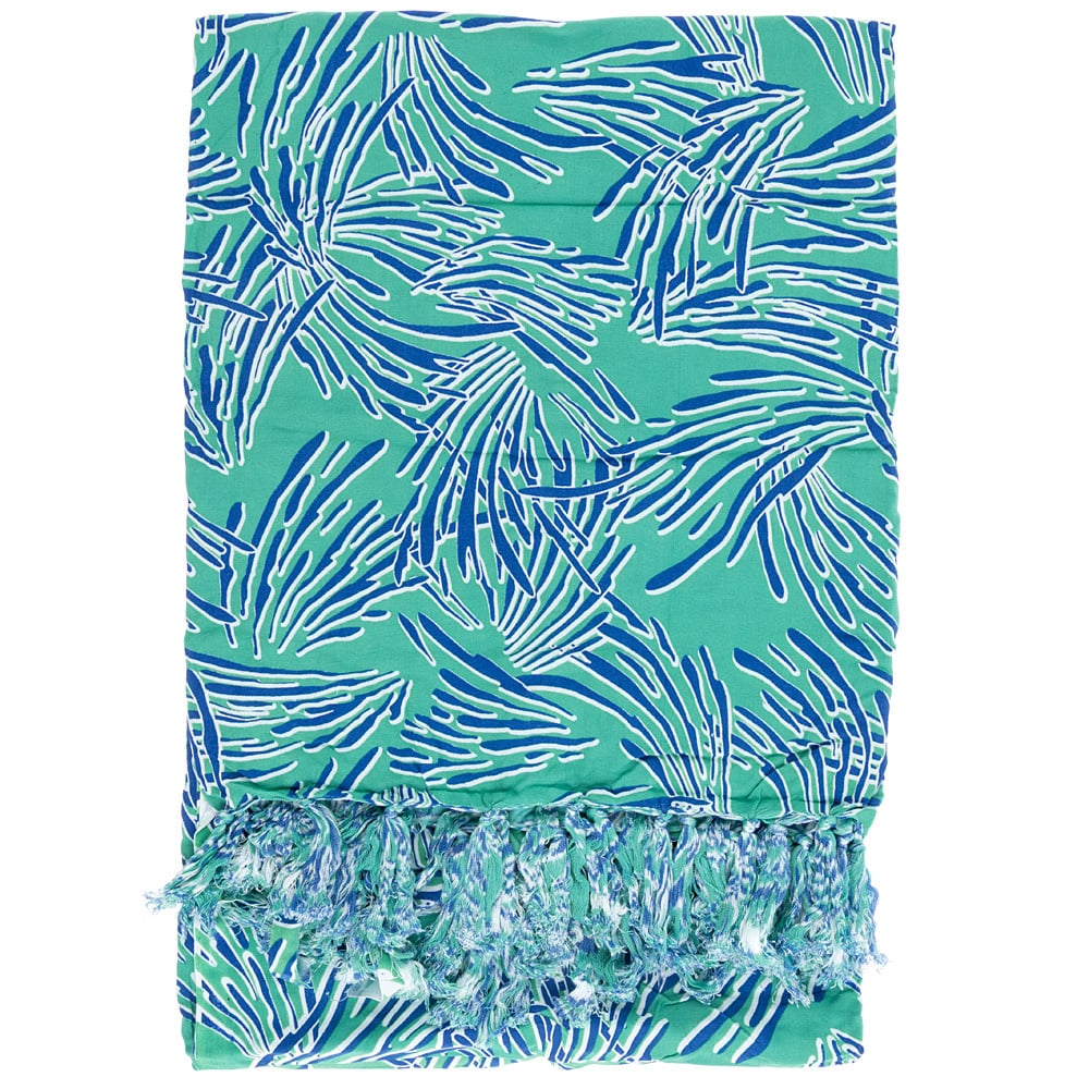 A folded turquoise fabric with a blue and white abstract leaf pattern and fringed tassels at the edge.