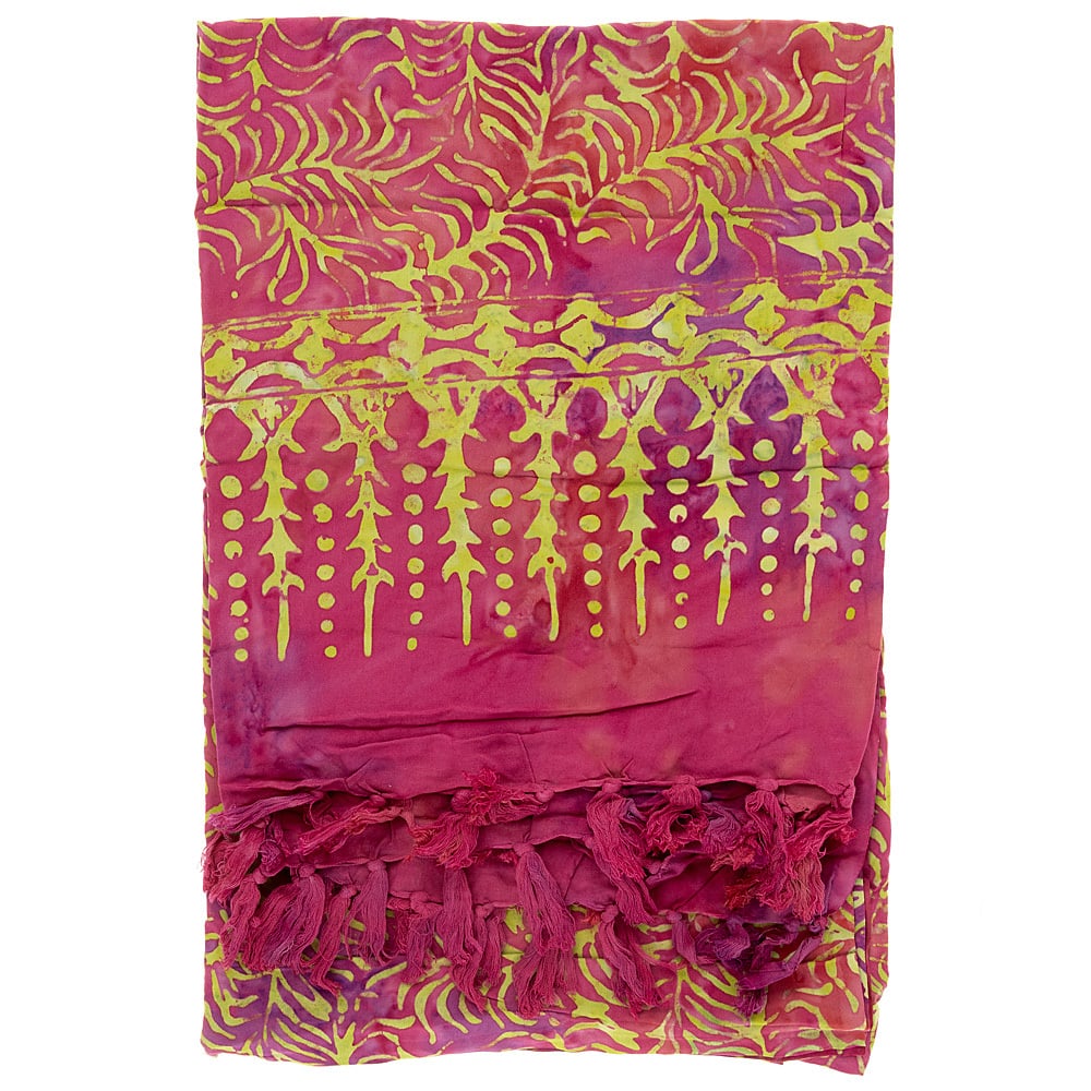 A folded pink and yellow patterned fabric with leafy and dotted designs and tassels along one edge.