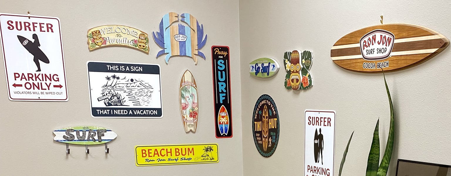 two beige walls of a room with a collection of various beach and surf-themed signs