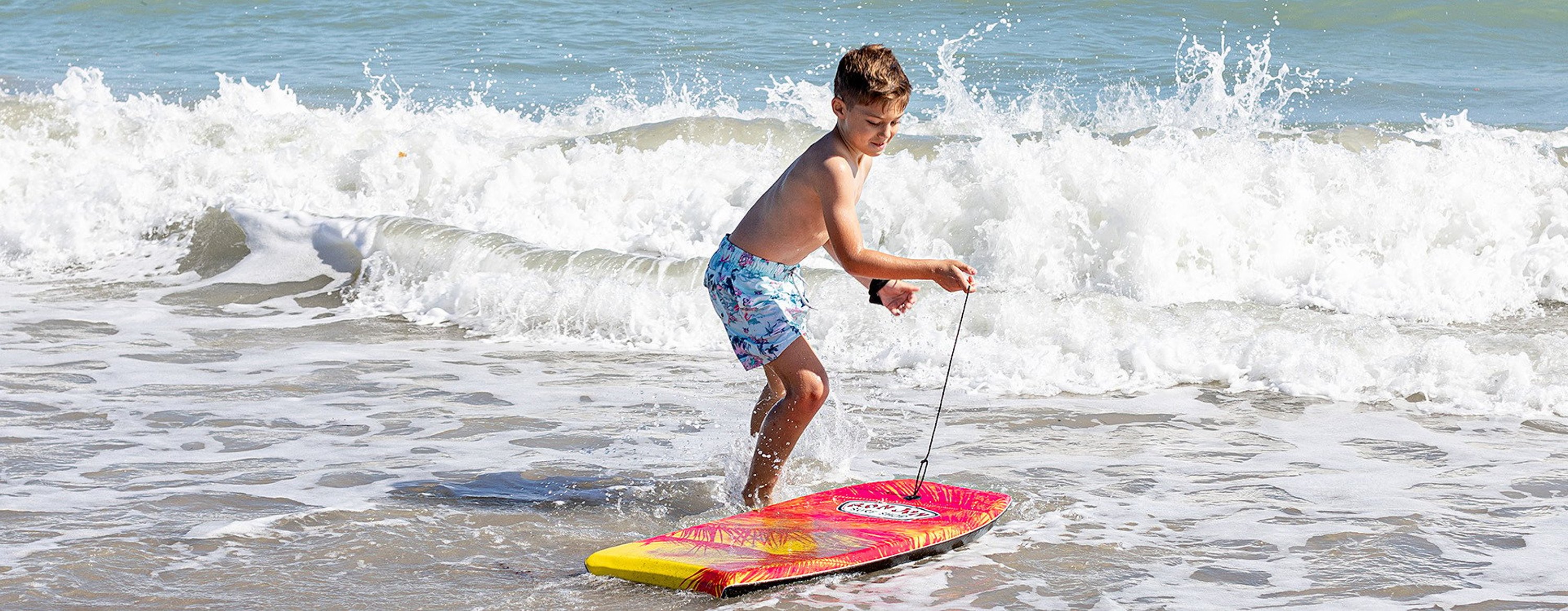 young boy at the ocean with a bodyboard