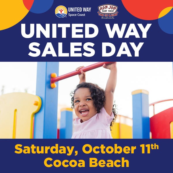A young girl smiles and hangs from playground bars under a banner promoting United Way Sales Day on Saturday, October 11th in Cocoa Beach.